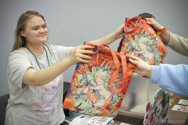 Волонтёр выдаёт гостям яркие пакеты с подарками на октябрьской Заре.